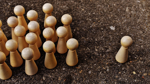 Gruppe von Holzfiguren und eine einzelne Holzfigur außerhalb der Gruppe