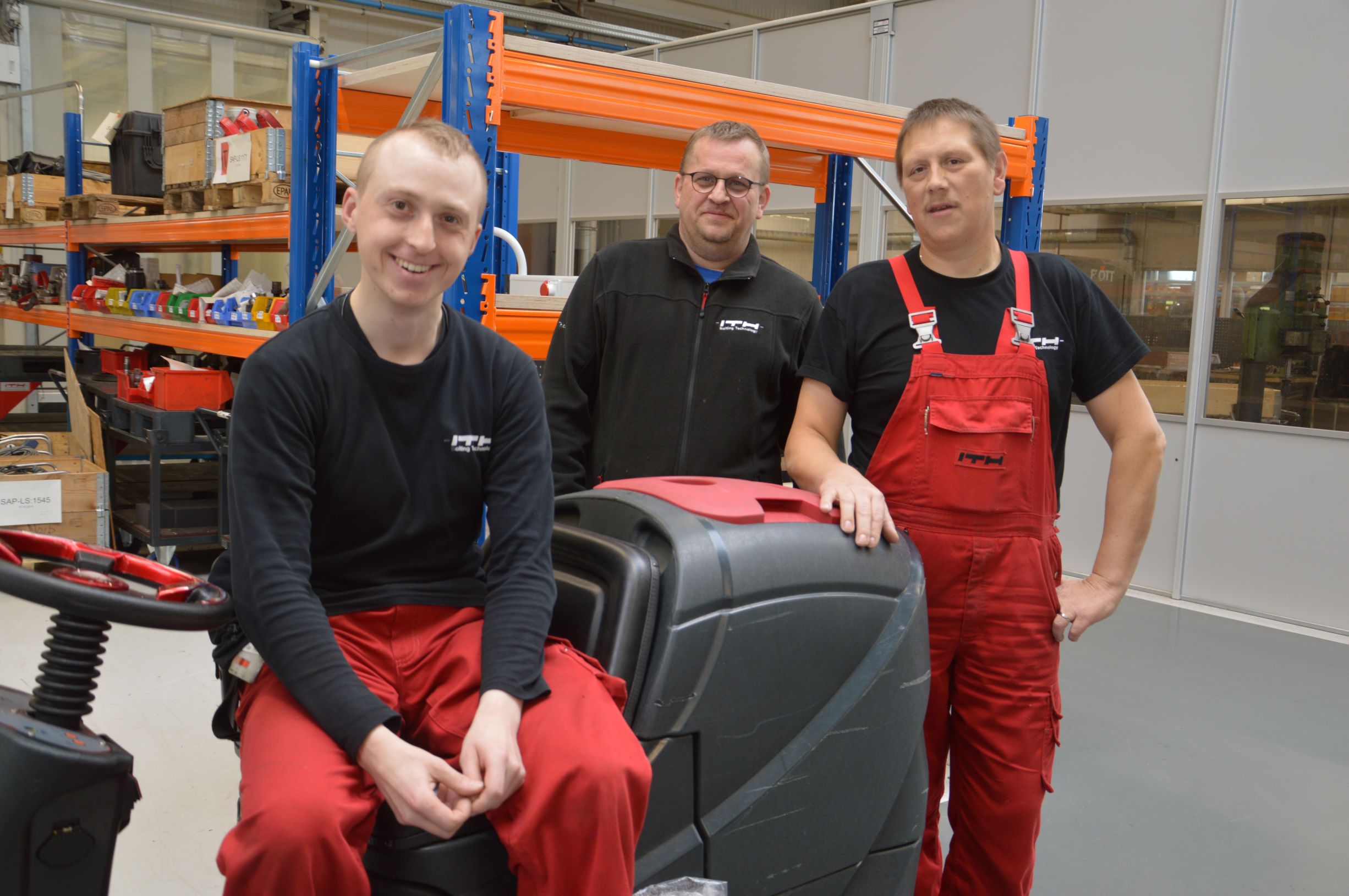 Das Foto zeigt links Jan-Peter Lübke auf seiner Reinigungsmaschine. Daneben stehen seine Kollegen Enrico Grabisnki und Martin Kramer.