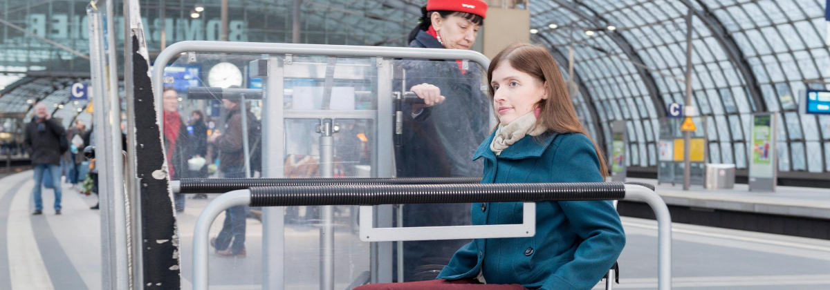 Eine Frau im Rollstuhl wird von einer Mitarbeiterin der Bahn in den Zug begleitet.