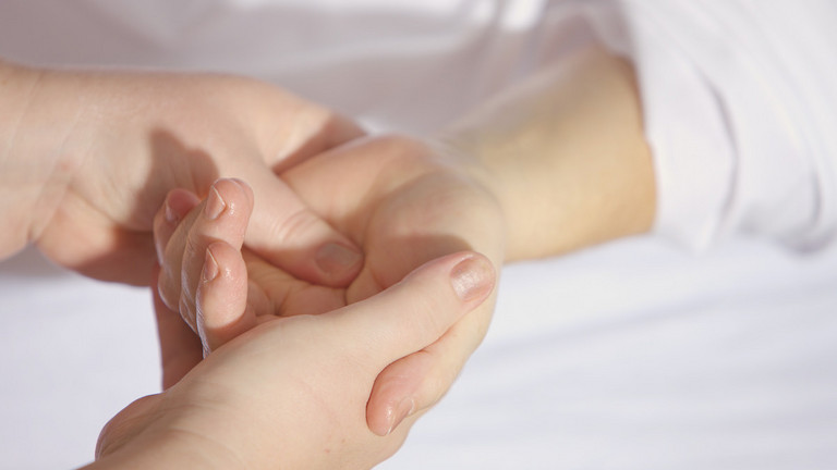 Eine Pflegeperson hält die Hand einer pflegebedürftigen Person. 