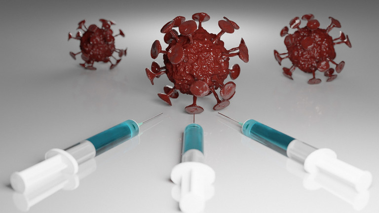 Das Bild zeigt drei Spritzen, die auf ein Modell des Coronavirus weisen.