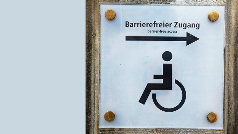 Das Foto zeigt das Symbol für einen Menschen im Rollstuhl. Ein Pfeil weist nach links. Darüber steht der Schriftzug Barrierefreier Zugang.