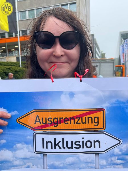 Inklusion- statt Ausgrenzung - Verkehrsschilder weisen die Richtung. Schild einer Demoteilnehmerin