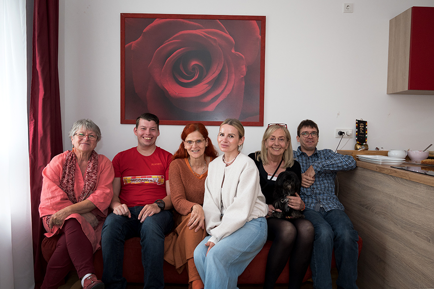 Sechs Bewohner*innen auf dem Sofa im Gemeinschaftsraum