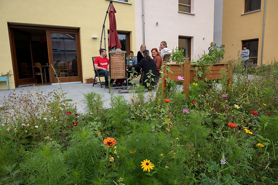 Terrasse vor dem Gemeinschaftsraum mit Blumenwiese im Vordergrund