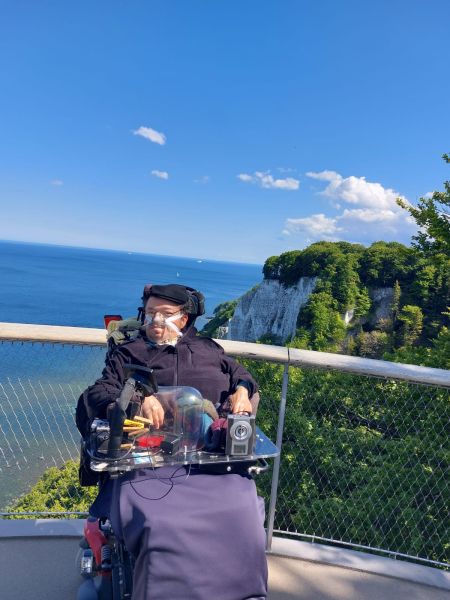  Mirko Dimastrogiovanni in seinem Rollstuhl - im Hintergrund sind Felsen und das Meer zu sehen.