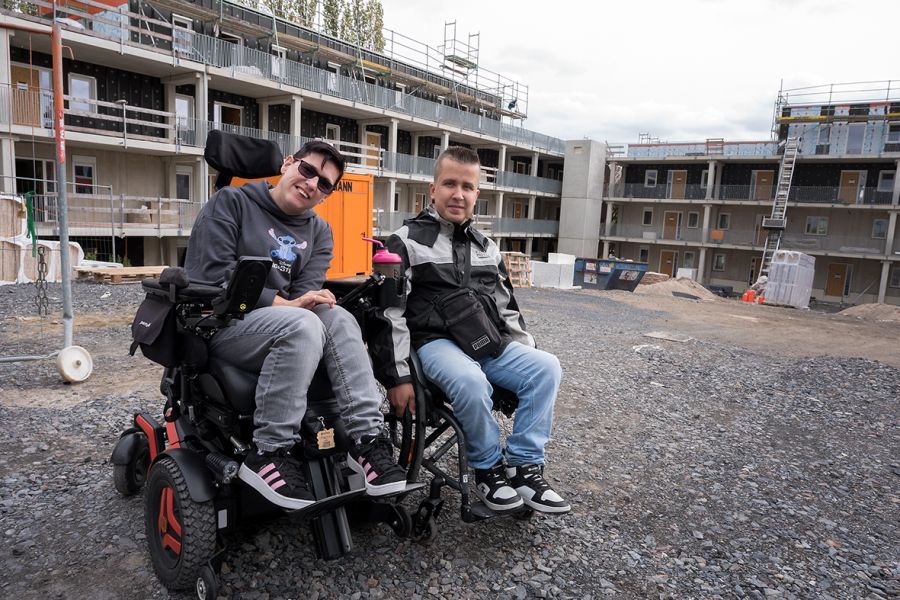 Ein Paar, beide Rollstuhlnutzer, sieht sich auf dem Baustellengelände um.