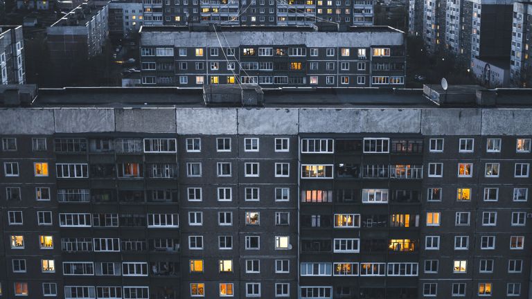 Häuserfassade mit beuchteten Fenstern.
