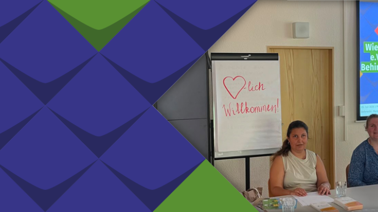 Diana Matzat und Maren Zebrowski sitzen als Referentinnen an einem Tisch mit Laptop und Notize. Hinter ihnen ist ein Flipchart mit "Herzlich Willkommen!" zu sehen, außerdem die Titelfolie einer Powerpointpräsentation