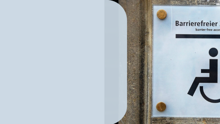 Eine Tafel mit einem gezeichneten Rollstuhl als Hinweisschild zu einem barrierefreien Eingang